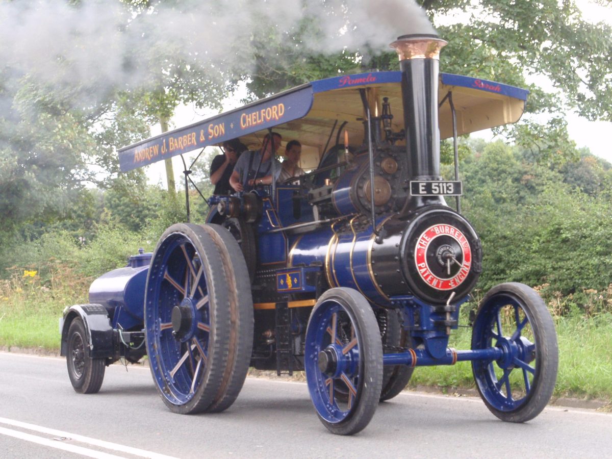 A full-size Burrell single crank compound road locomotive in blue livery, in steam and towing its water cart along a road near Chelford, Cheshire